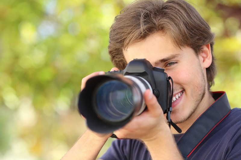Photographer photographing and learning with a dslr digital camera with a green background